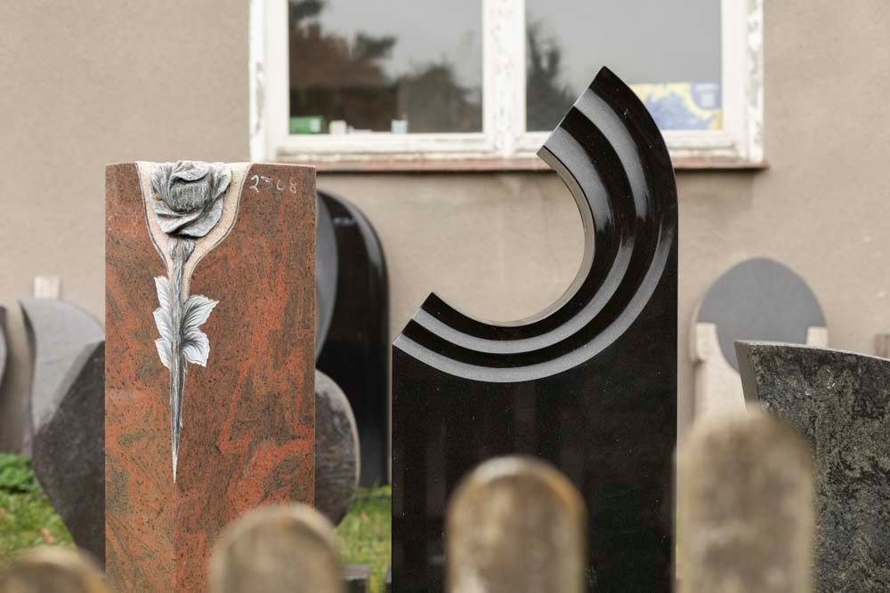 Vor einem Gebäude steht eine Gruppe Grabsteine.