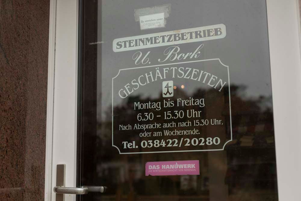 Eine Glastür mit einem Schild darauf, auf dem steht: Geschäftszeiten