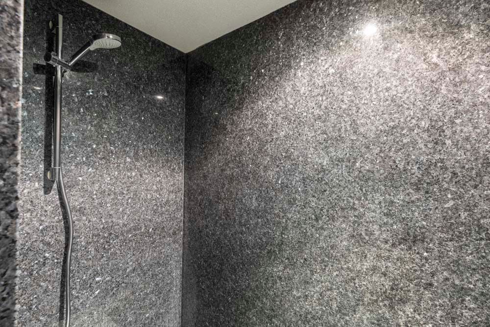 Eine Duschkabine mit Duschkopf und schwarzer Wand.