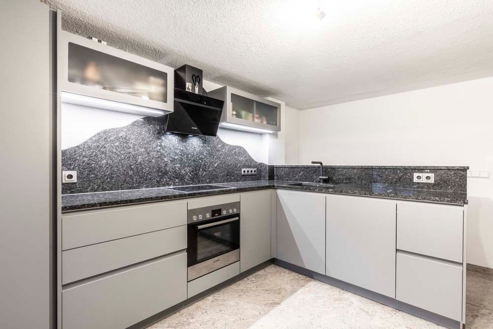 Eine Küche mit Geräten aus Edelstahl und Arbeitsplatten aus Granit.