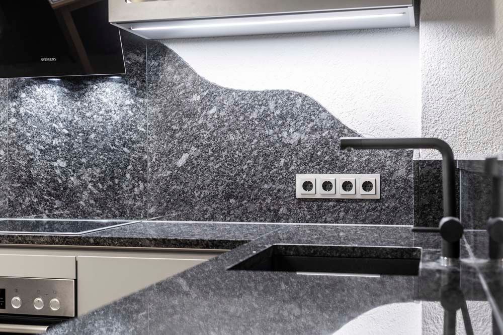 Eine Küche mit Granitarbeitsplatten, Geräten aus Edelstahl und einer schwarzen Spüle.