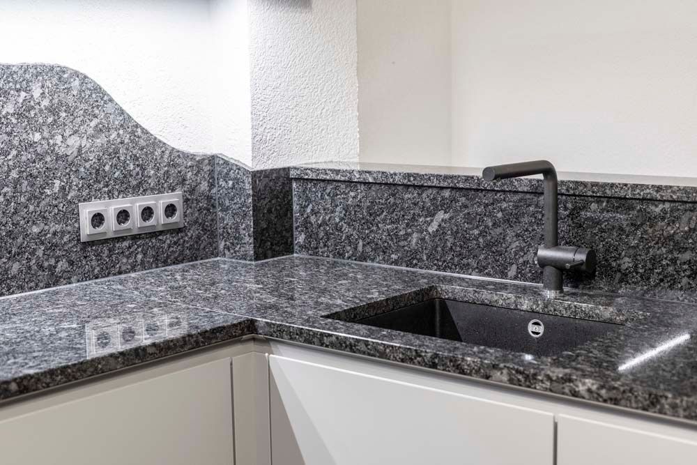 Eine Küche mit Granitarbeitsplatten und einer schwarzen Spüle.
