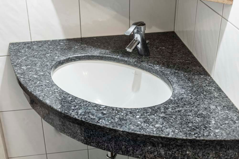 Ein Waschbecken mit Wasserhahn auf einer Arbeitsplatte aus Granit.