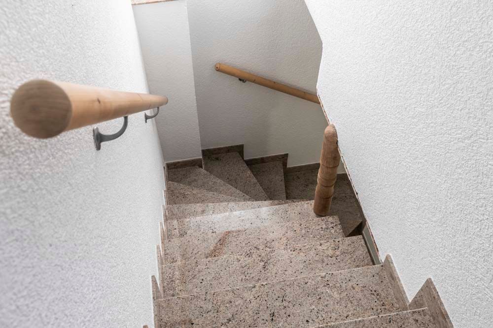 Die Treppe ist aus Granit und hat ein Holzgeländer.