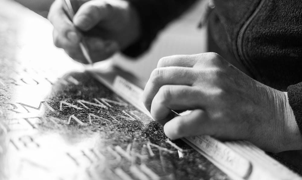 Eine Person schreibt mit einem Lineal auf ein Blatt Papier.