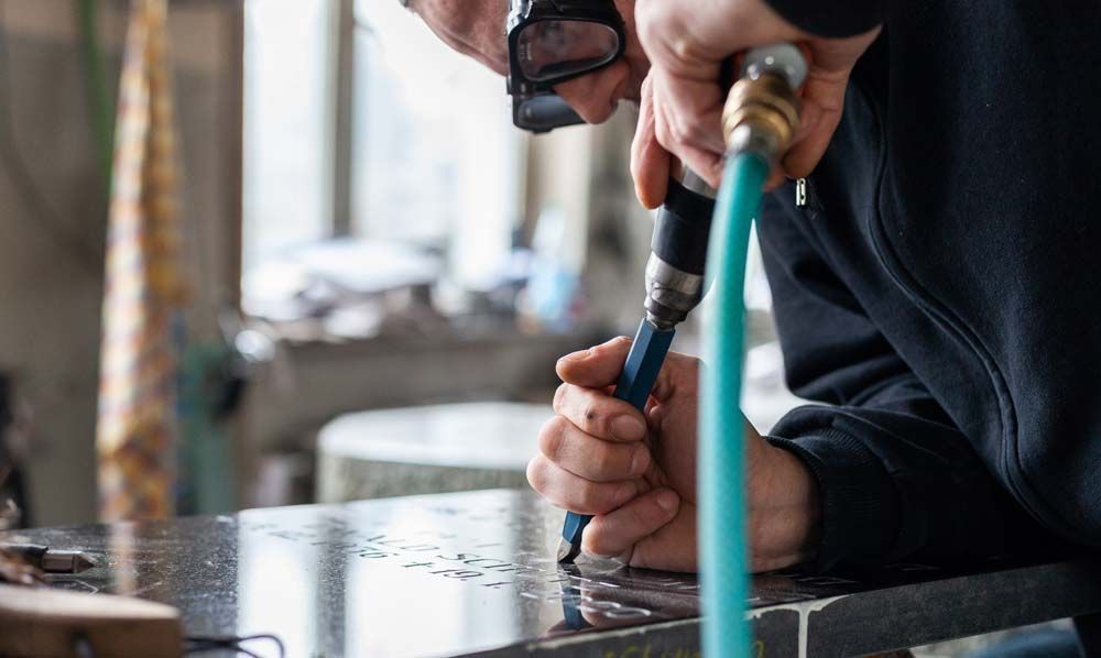 Ein Mann bohrt mit einem Schlauch ein Loch in ein Stück Metall.