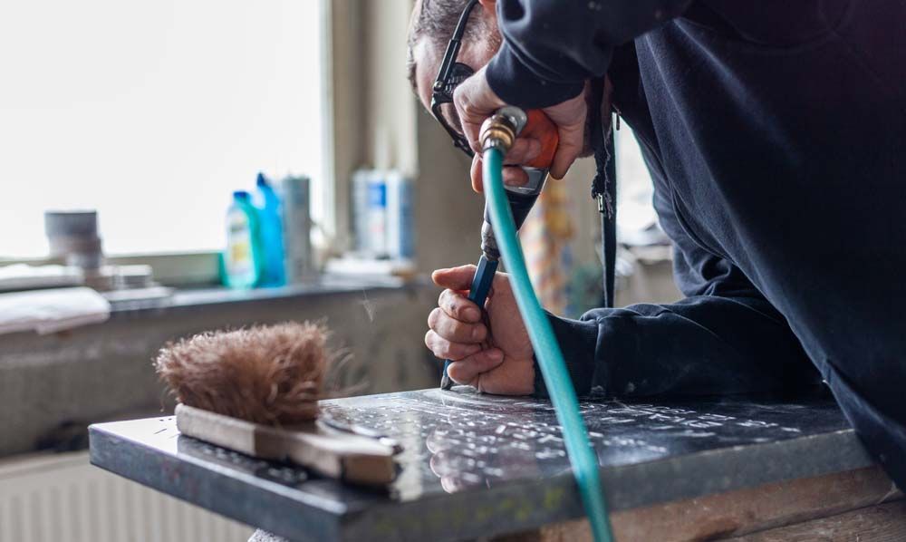 Ein Mann schneidet mit einem Schlauch ein Stück Stein heraus.