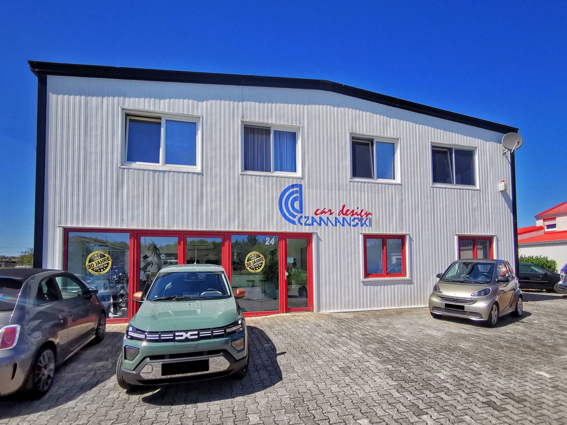 Firmengebäude von Car Design Czarninski mit geparkten Fahrzeugen – Kontakt und Anfahrt zur Werkstatt