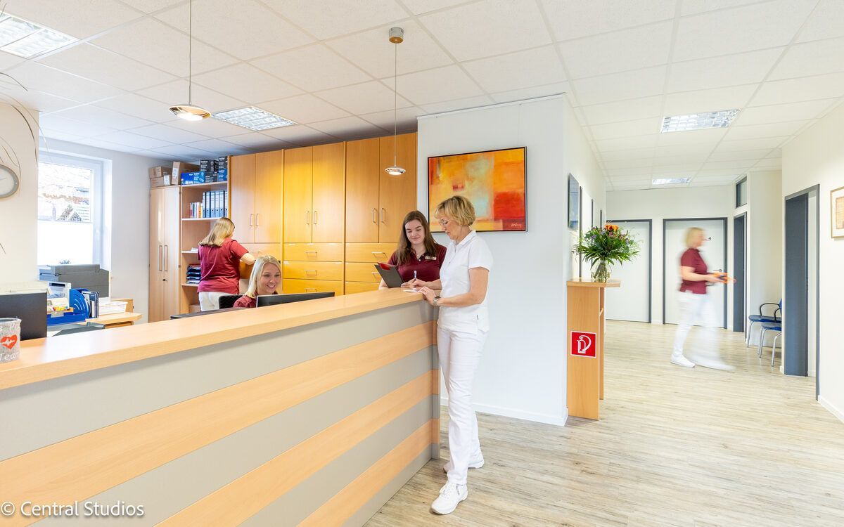 Eine Frau steht an einem Tresen in einer Hausarztpraxis für Allgemeinmedizin