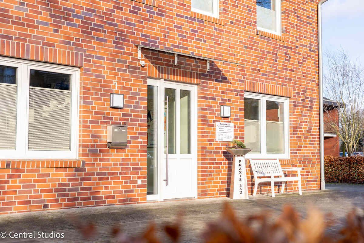 Hausarztpraxis für Allgemeinmedizin mit einer weißen Bank davor.