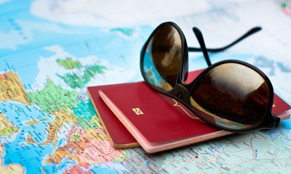 Gafas de sol apoyadas sobre dos pasaportes rojos, encima de un mapa de Europa.