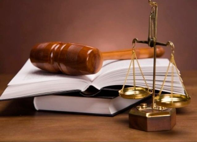 Mazo de madera y balanza encima de libros de derecho abiertos.