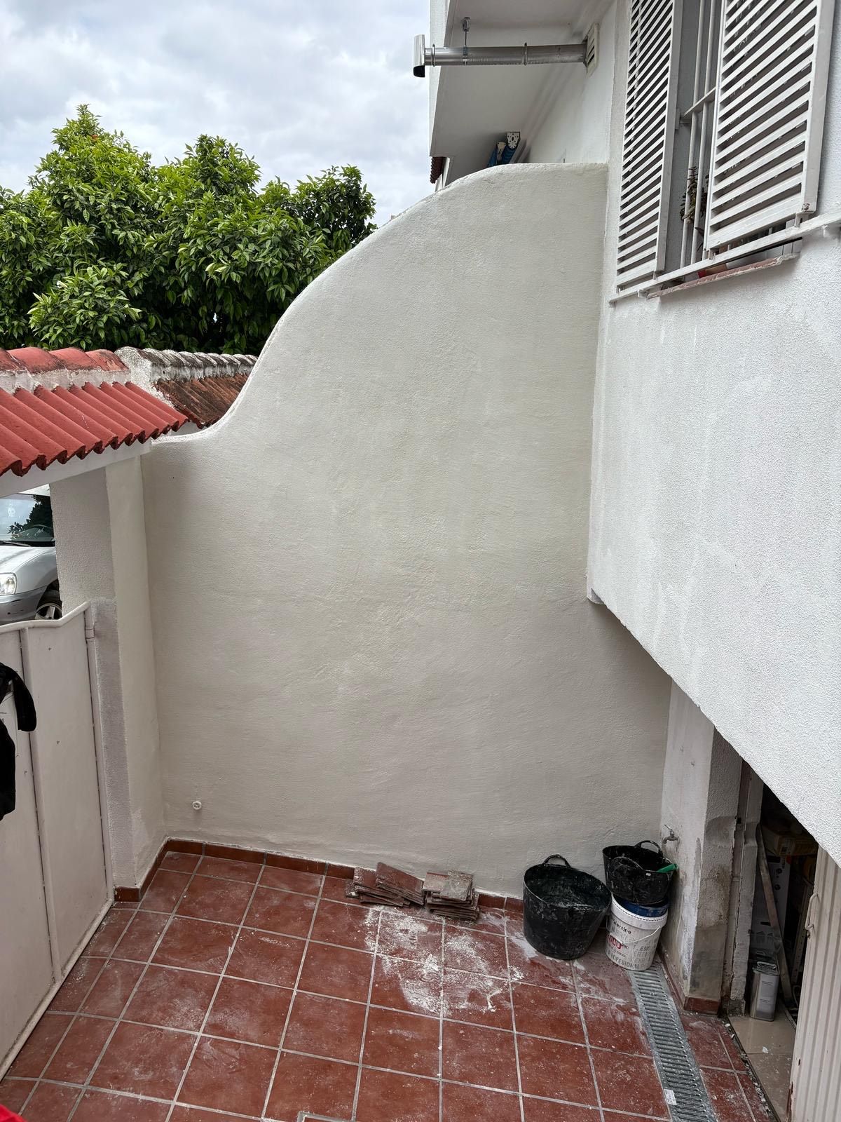 Un edificio blanco con suelo de baldosas rojas y una pared blanca.