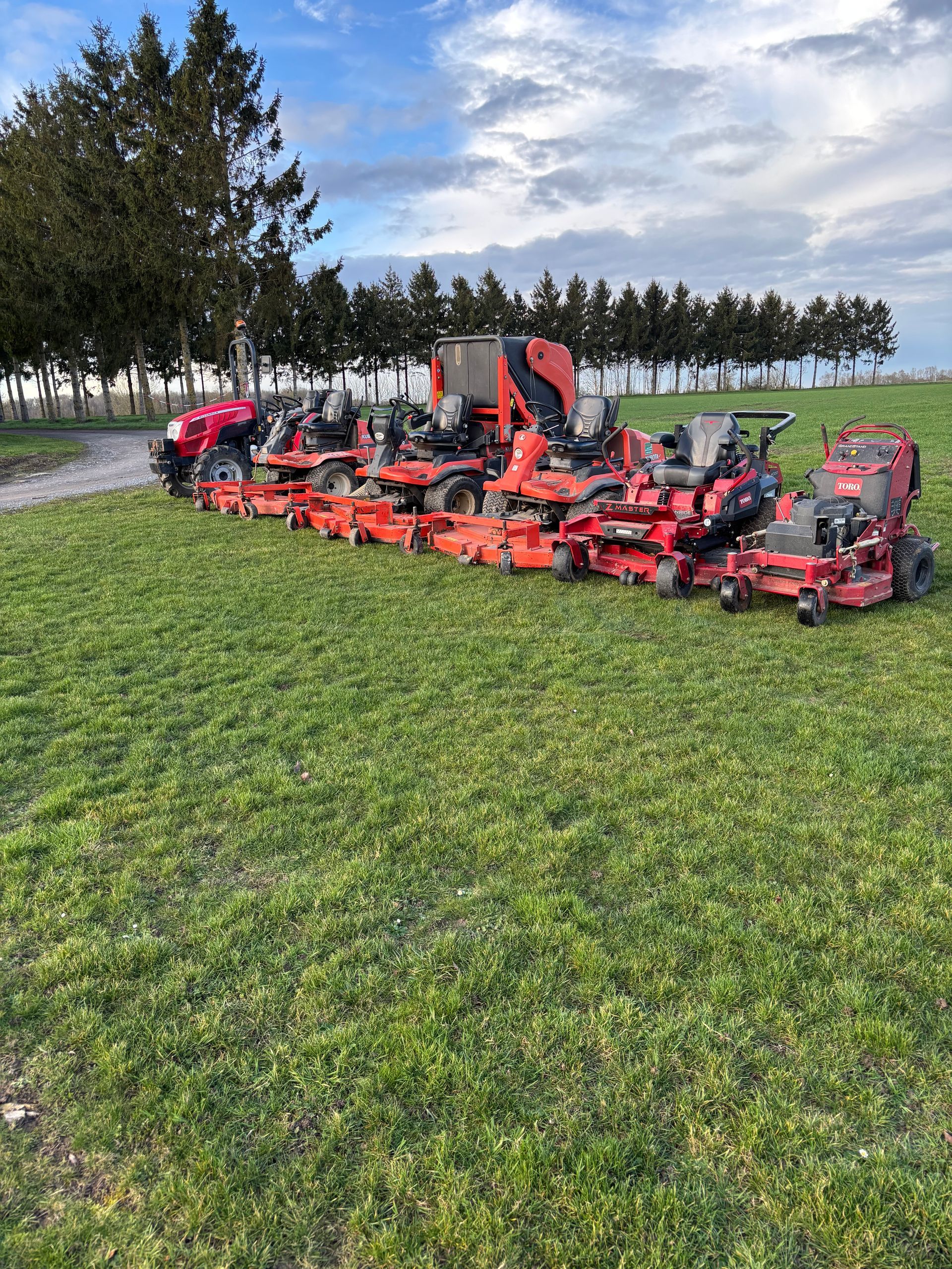 Une pelouse verdoyante, luxuriante et sinueuse, bordée d'un jardin et d'un chemin de gravier, le tout entouré de verdure.