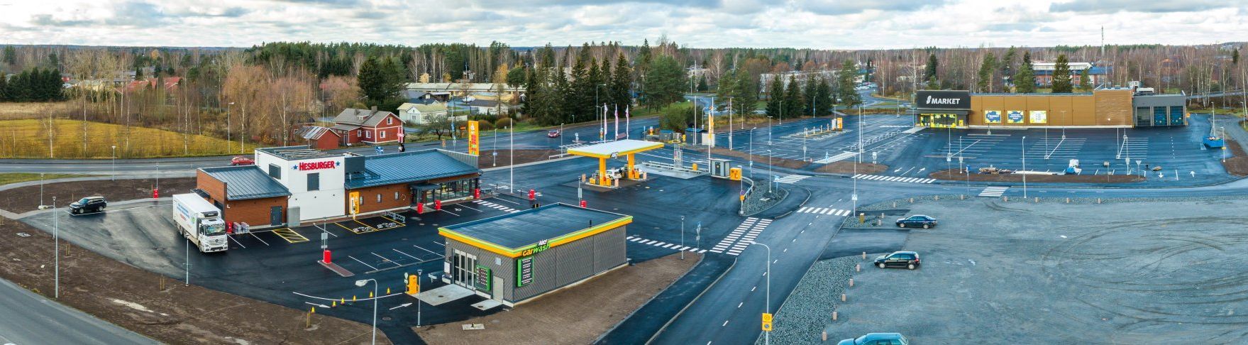 Laaja ilmakuva rakennustyömaasta, jolla on kuorma-autoja, laitteita ja suuri avoin soratontti hämärässä