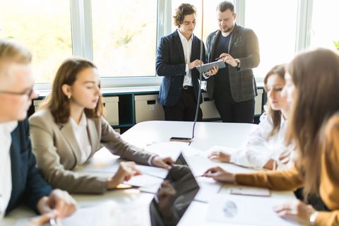 Un grupo de personas están sentadas alrededor de una mesa teniendo una reunión.