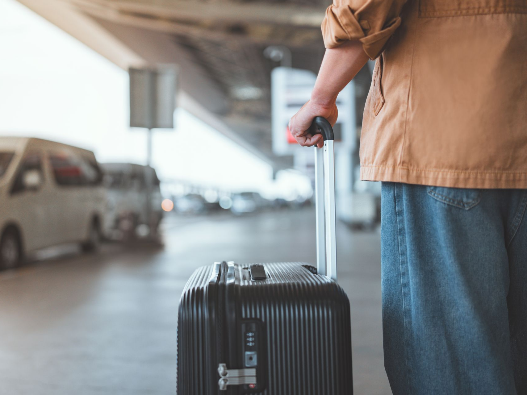 Personne tenant une valise noire, debout dans un aéroport.