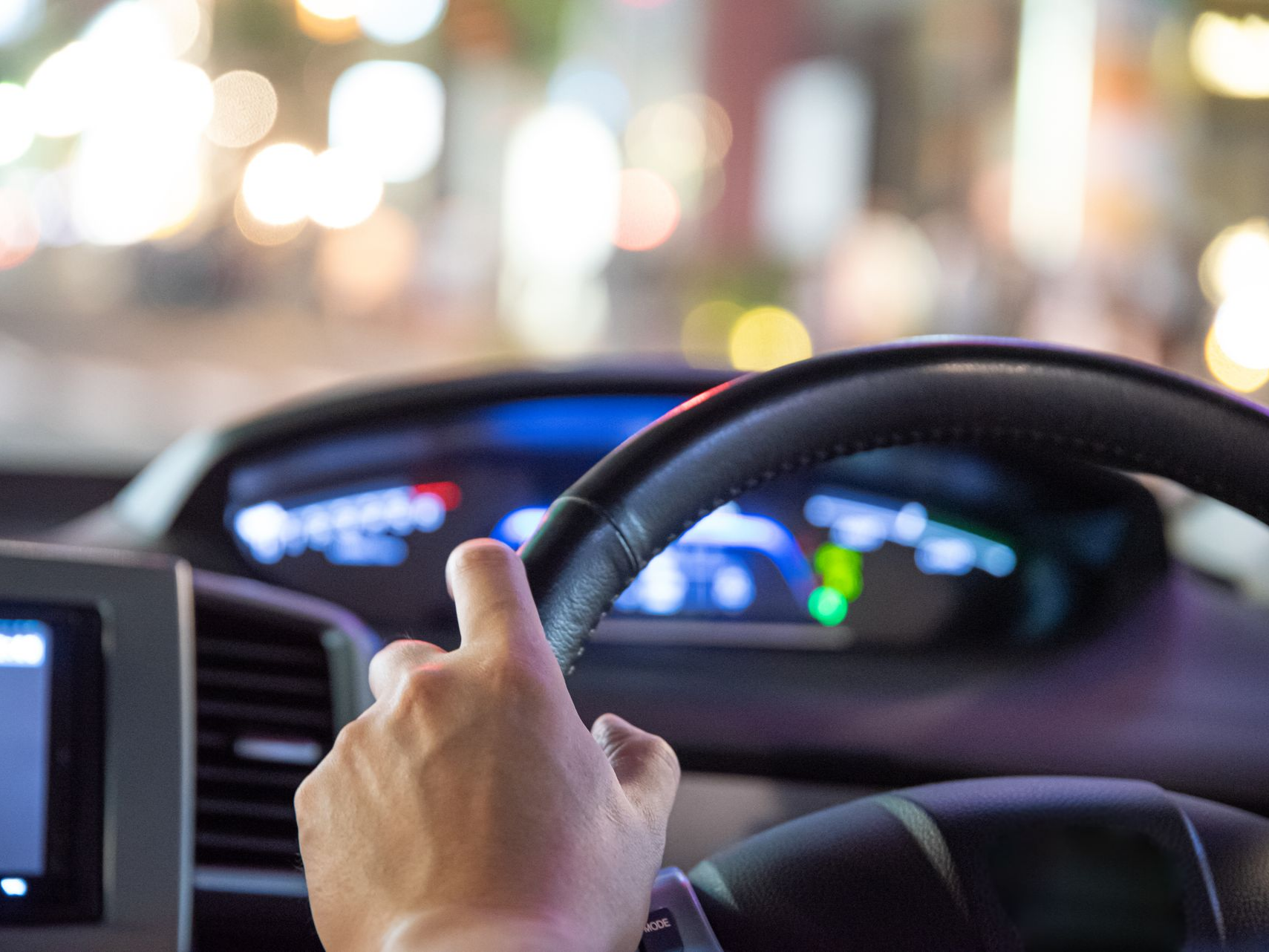 Une main agrippant un volant à l'intérieur d'une voiture.