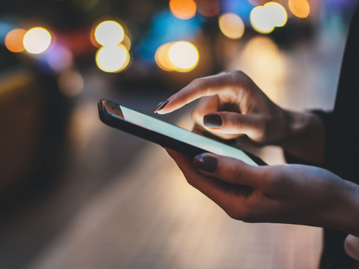 Gros plan sur des mains tenant et utilisant un smartphone.