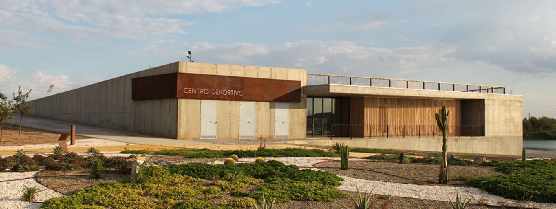 Un gran edificio con muchas ventanas está rodeado de plantas y rocas.