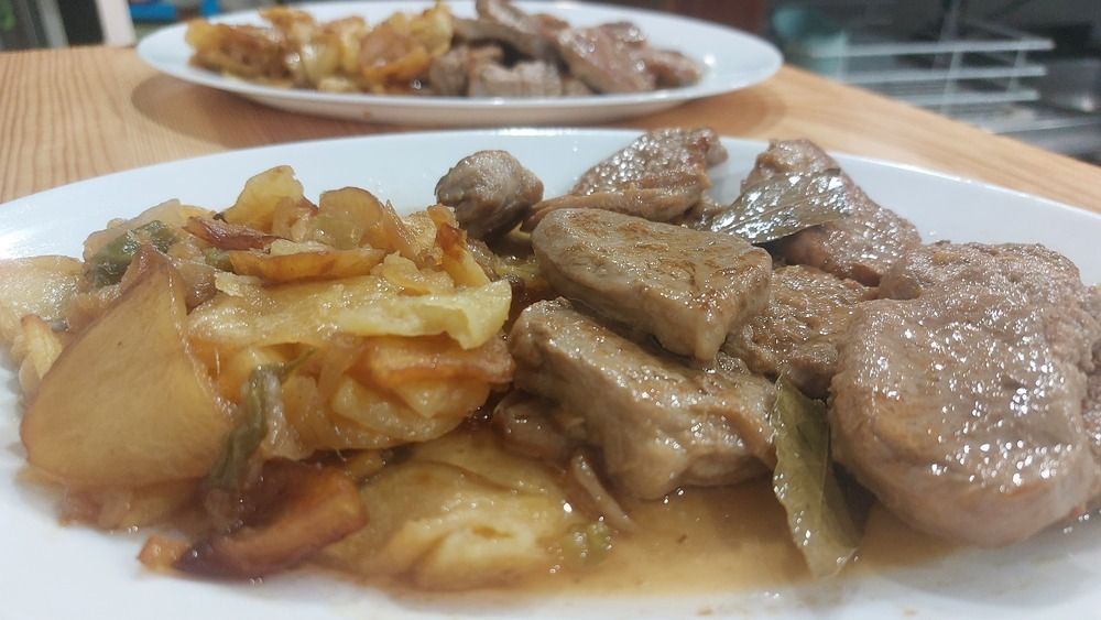 Un plato de comida con carne y patatas en una mesa.
