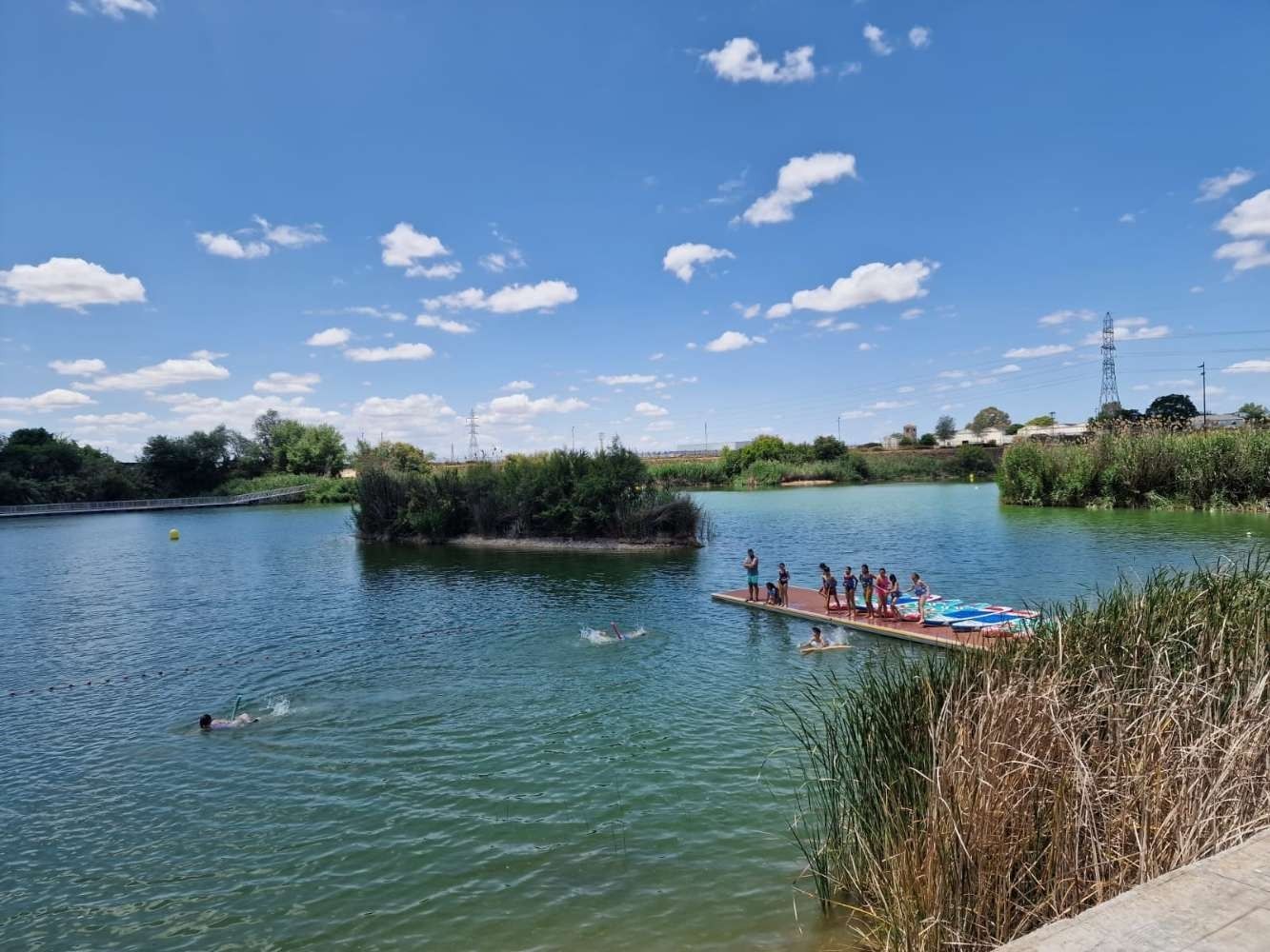 Un grupo de personas está de pie en un muelle en medio de un lago.