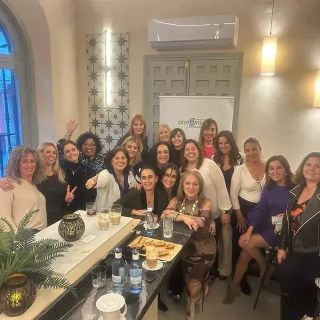 Un grupo de mujeres posa para una fotografía en una habitación.