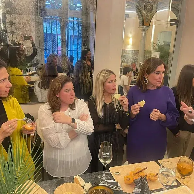Un grupo de mujeres están de pie alrededor de una mesa comiendo comida.