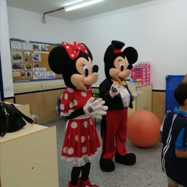 Dos mascotas de Mickey Mouse paradas una al lado de la otra en una habitación