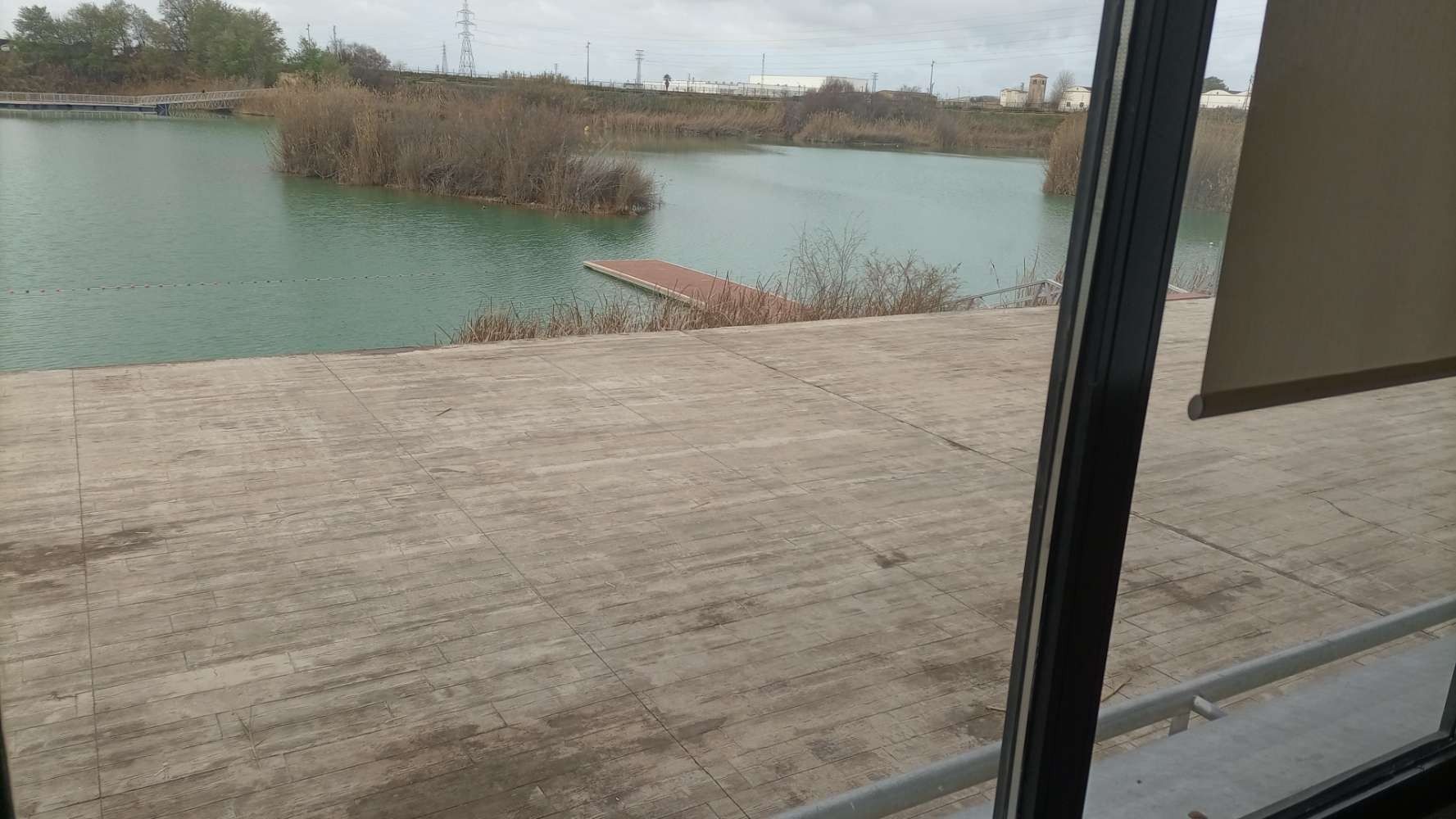 Una vista de un lago a través de una ventana con un muelle al fondo.