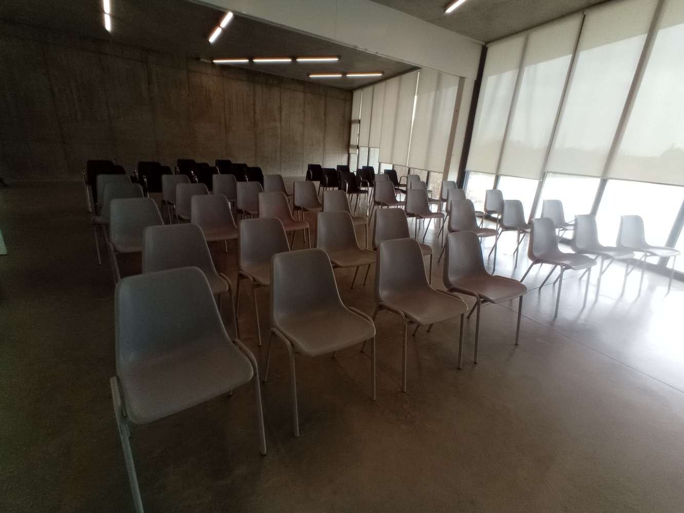 Filas de sillas en una habitación con muchas ventanas