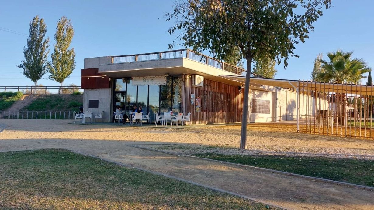 Un gran edificio con muchas ventanas está rodeado de árboles y césped.