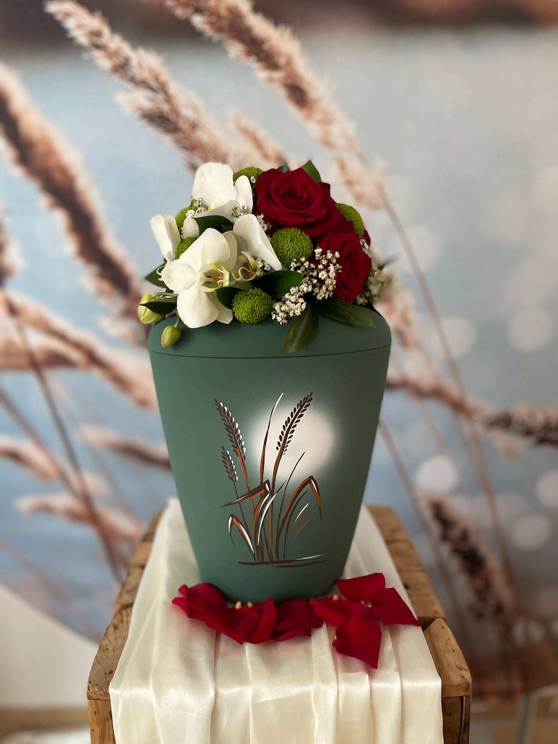 Weiße Orchideen und rote Rosen auf einer Urne