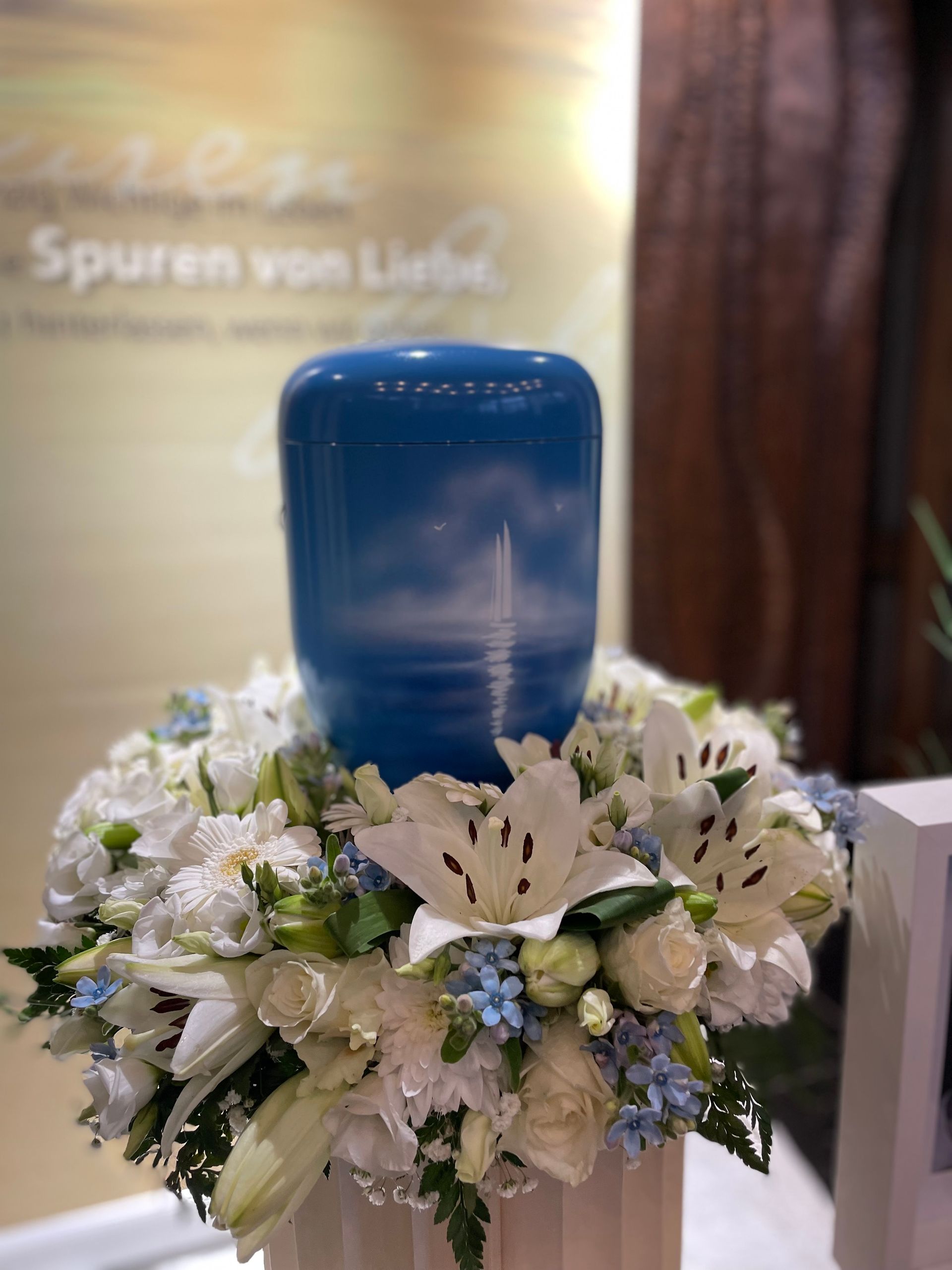 Blaue Urne mit weißem Blumenkranz