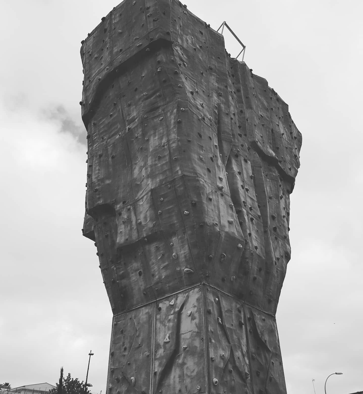 Escultura abstracta alta con forma de roca contra un cielo nublado.