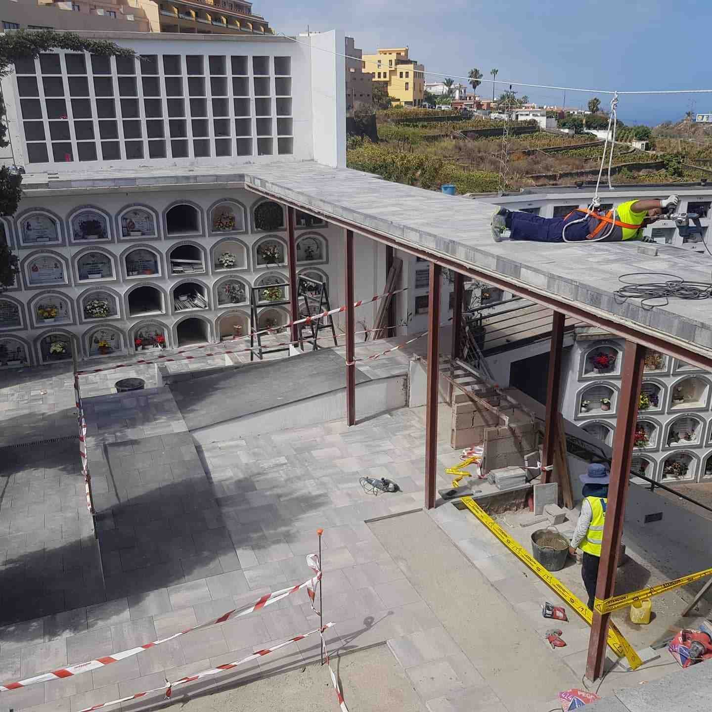 Obra en construcción en la azotea con losas de hormigón, soportes metálicos y trabajadores con llamativos trajes de seguridad.