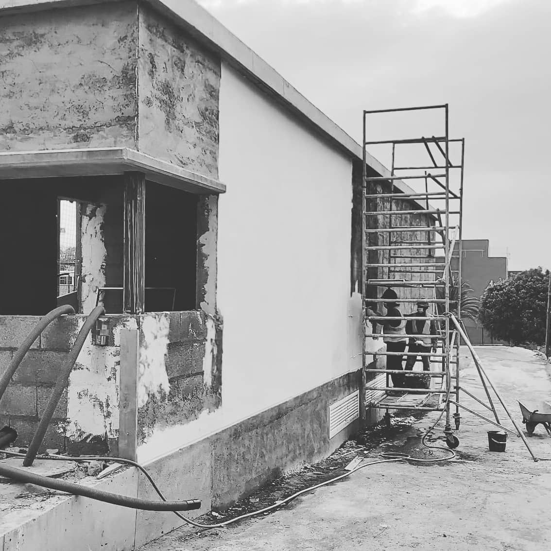 Exterior de un edificio en construcción con andamios, paredes sin terminar y una abertura para una ventana.