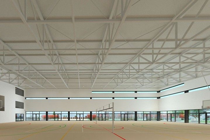 Pabellón deportivo interior vacío con techo alto de vigas blancas y paredes de vidrio en el lado opuesto.