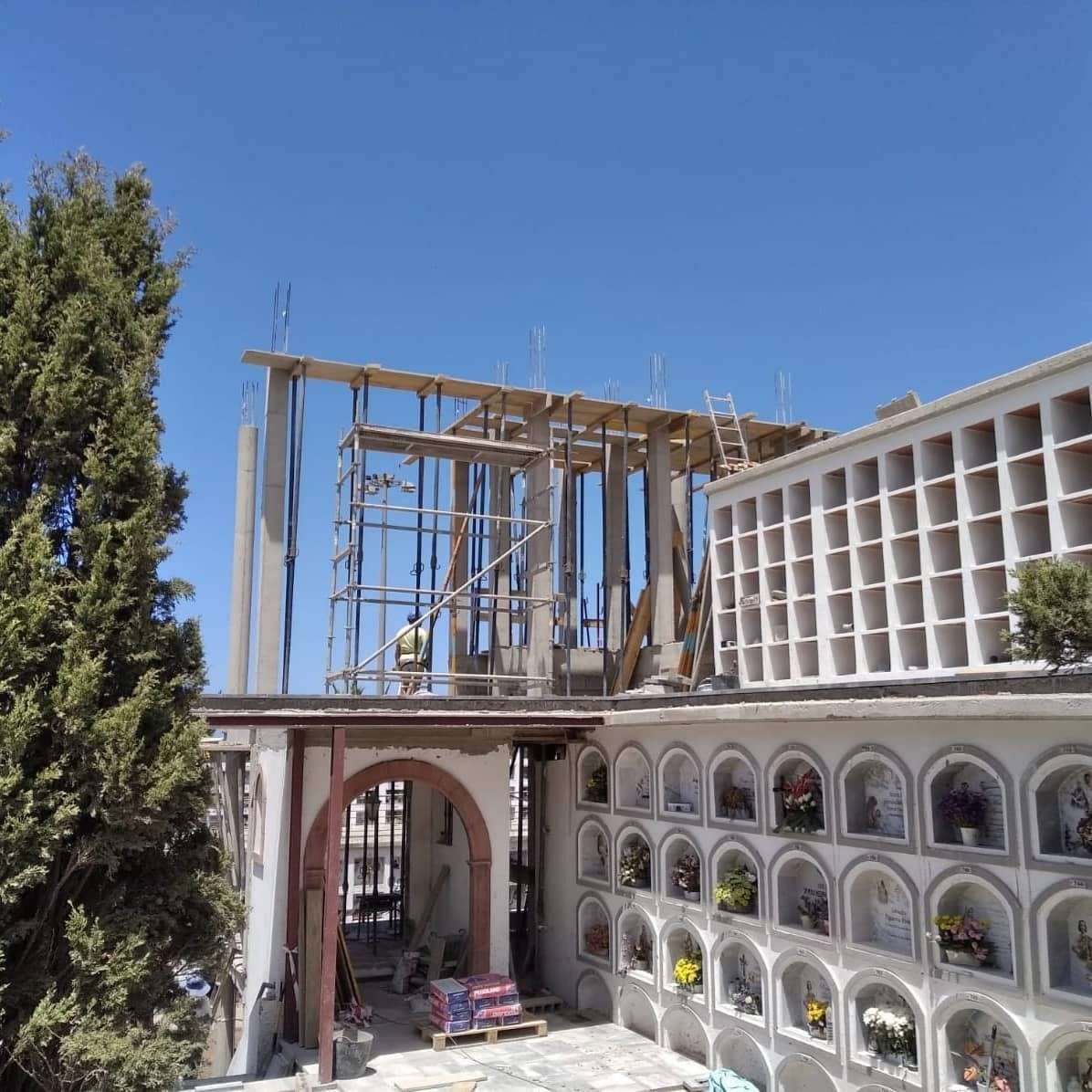 Patio con columnata arqueada y edificio blanco en construcción contra un cielo azul