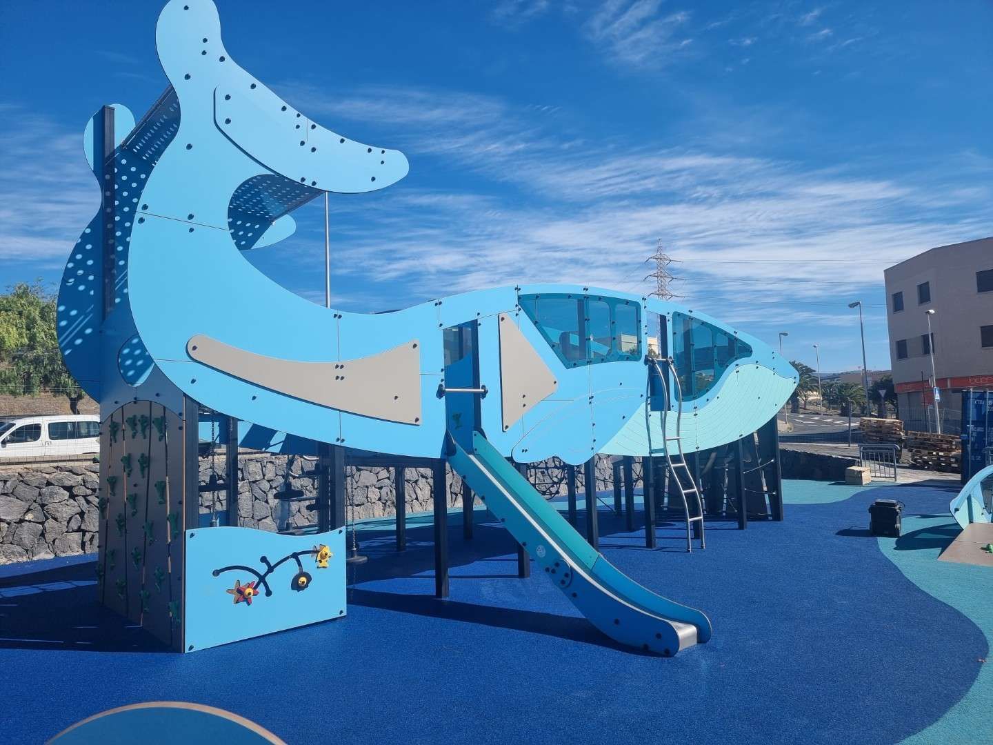 Un parque infantil con forma de ballena azul y un tobogán en un día soleado y brillante.