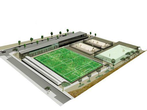 Vista aérea de un complejo de campos de fútbol con gradas, edificios, árboles y zonas de aparcamiento.