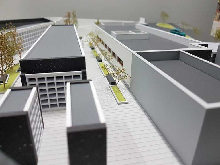 Maqueta arquitectónica de un complejo de edificios moderno con pasarelas y árboles.