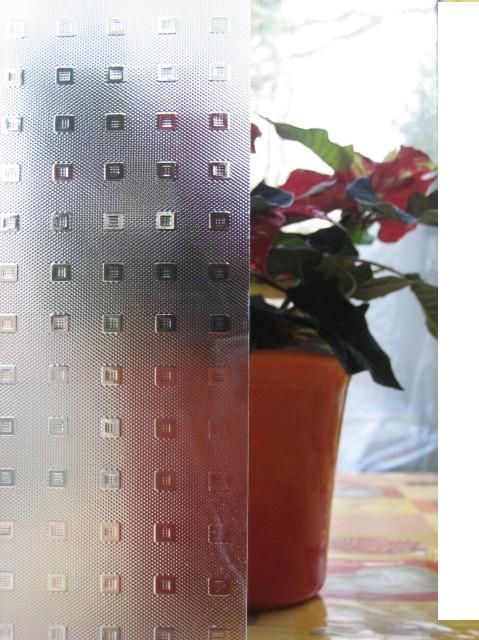 Glas mit Muster vor Blumentopf mit roten Blumen