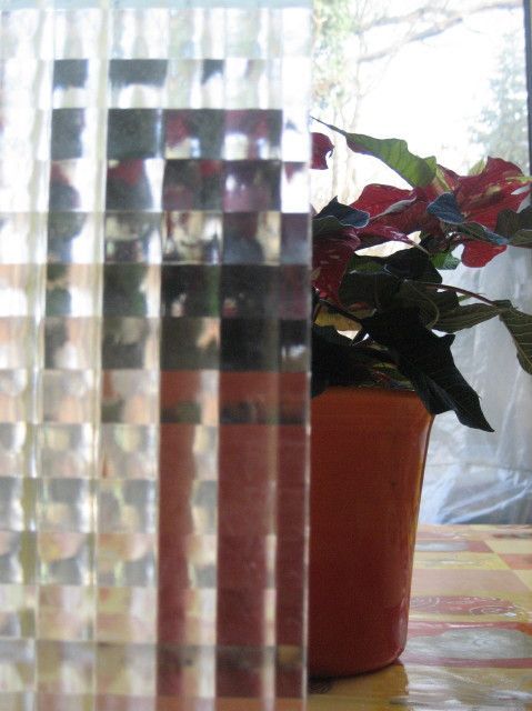 Glas mit skurrilem Muster vor Blumentopf