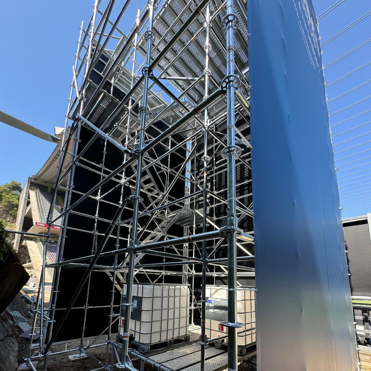 Structure d'échafaudage à l'intérieur d'un entrepôt sombre. La lumière du soleil filtre à travers une fenêtre en hauteur.