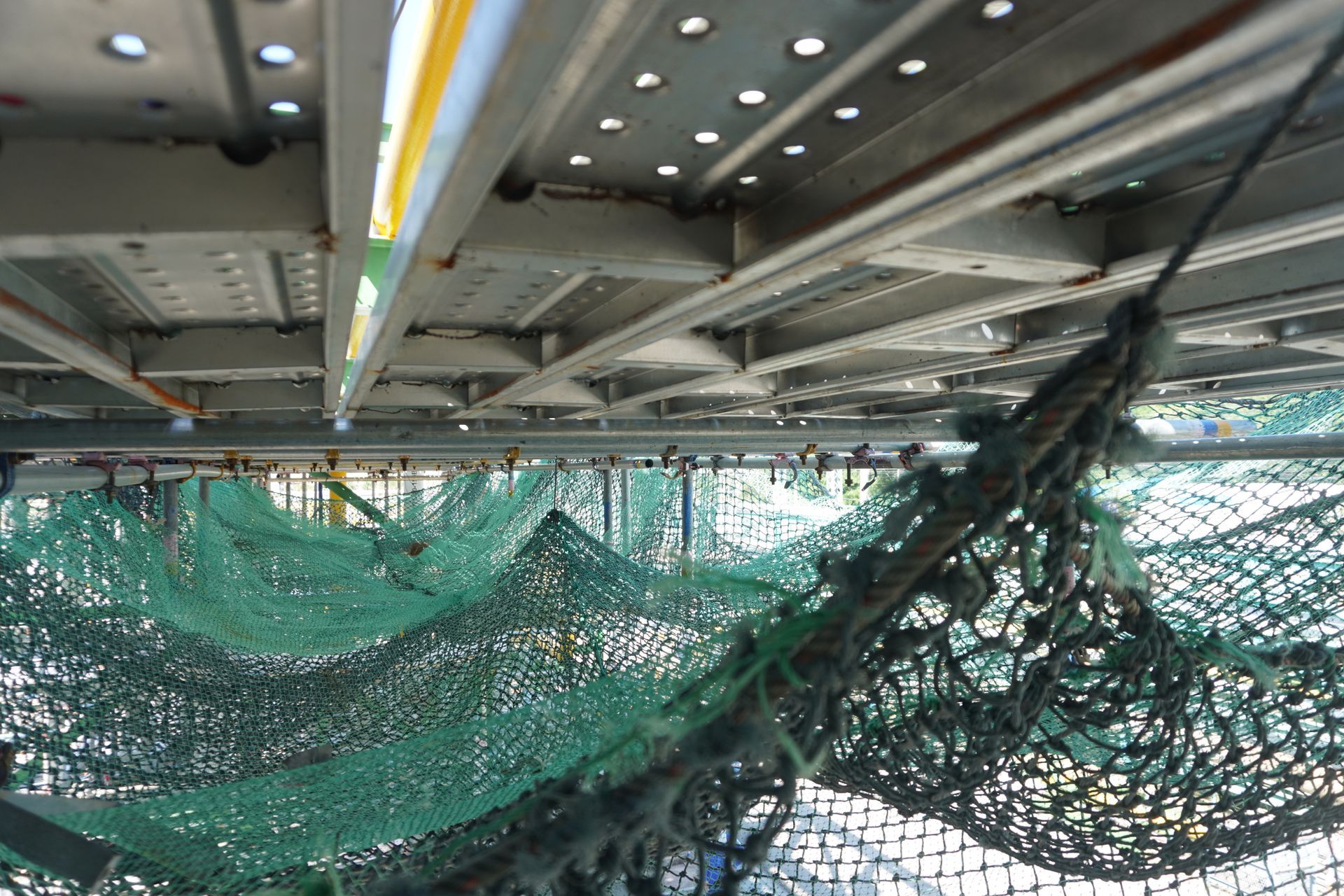 Échafaudage métallique au-dessus, filet vert en dessous.