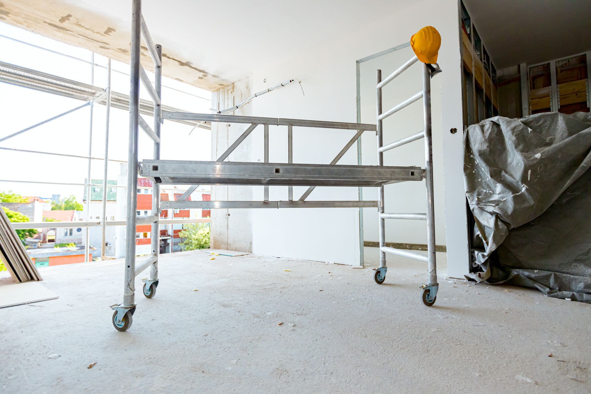 Échafaudage à l'intérieur d'une pièce en construction, avec un casque de chantier jaune au sommet.