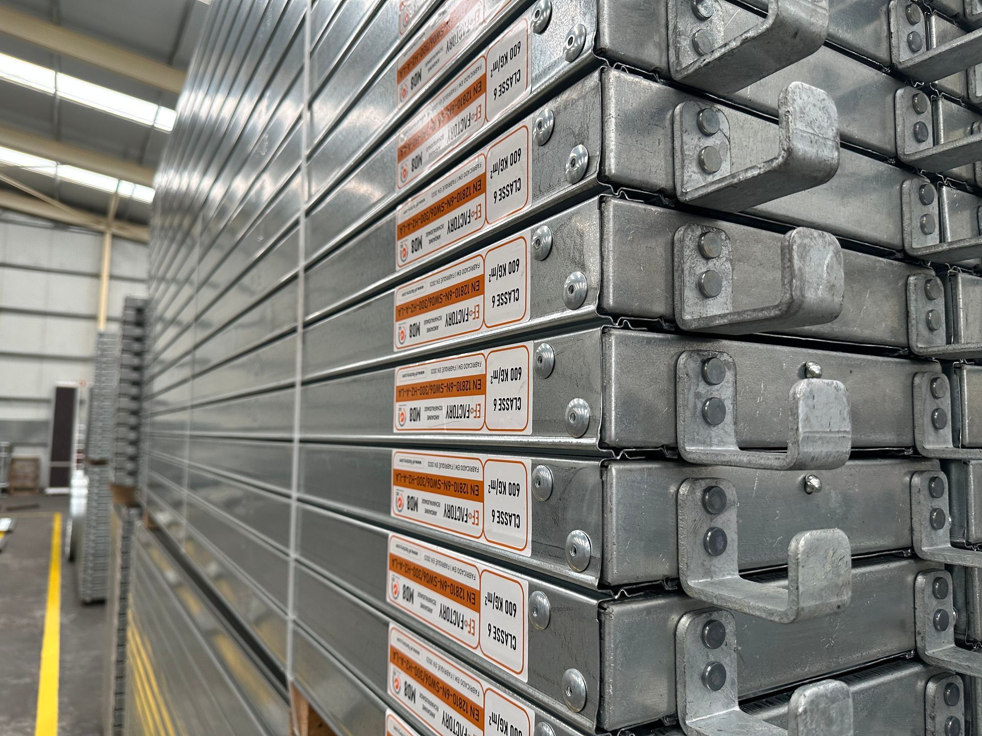 Bâtiment en rénovation avec échafaudages, bardage jaune pâle, pelouse verte, arbre et ciel bleu.