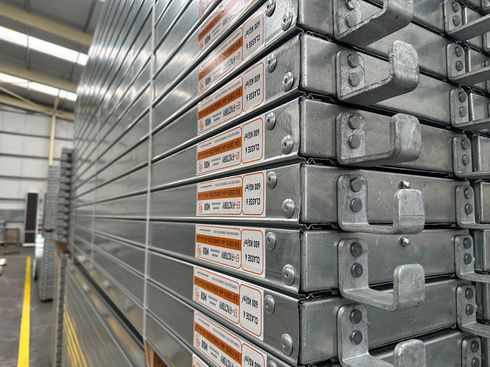 Bâtiment en rénovation avec échafaudages, bardage jaune pâle, pelouse verte, arbre et ciel bleu.