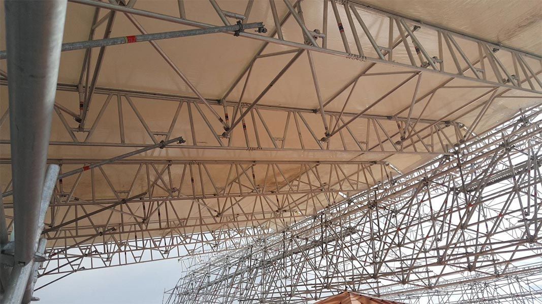 Échafaudage métallique soutenant une canopée en tissu blanc.